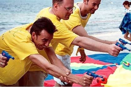 Mitarbeiterteam bei einem Wasserpistolen-Wettbewerb während Teamevent am Ostseestrand