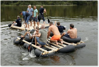 Mitarbeiterteam mit selbstgebauten Flößen unterwegs Authentisches Teambuilding: Mitarbeit mit selbstgebauten Flößen unterwegs