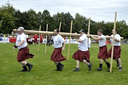 Highland Games als Incentive für "starke Teams" Gruppe von Mitarbeitern mit Baumstamm bei schottischen Highland Games