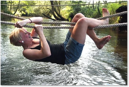 Mitarbeiterin überquert Bach bei Survival Training Teamtraining: Mitarbeiterin überquert Bach bei Survival Training
