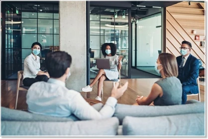 Mitarbeiterteam mit Masken bei einem Meeting während der Corona-Pandemie Mitarbeiterteam mit Masken bei einem Meeting während der Corona-Pandemie