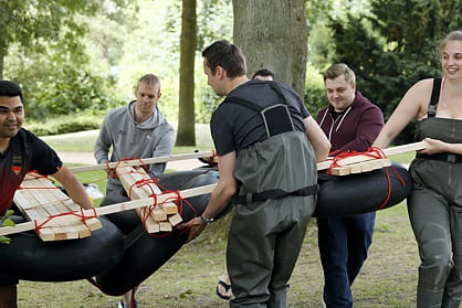 Mitarbeiterteam trägt fertiges Floß an die Alster