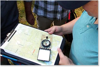 Führungskraft bei der Orientierung mit Karte und Kompass während eines Outdoor Trainings